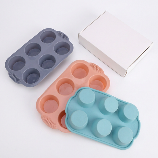 Three colored six-cavity silicone cake molds with plain white box on white background