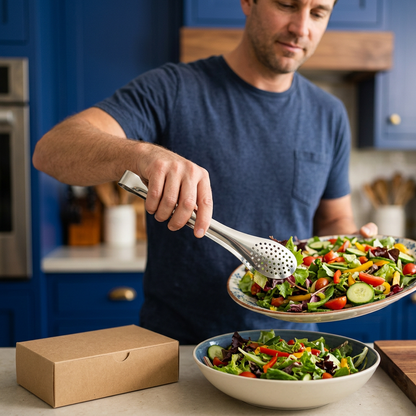 Male home cook serving salad with stainless steel kitchen tongs